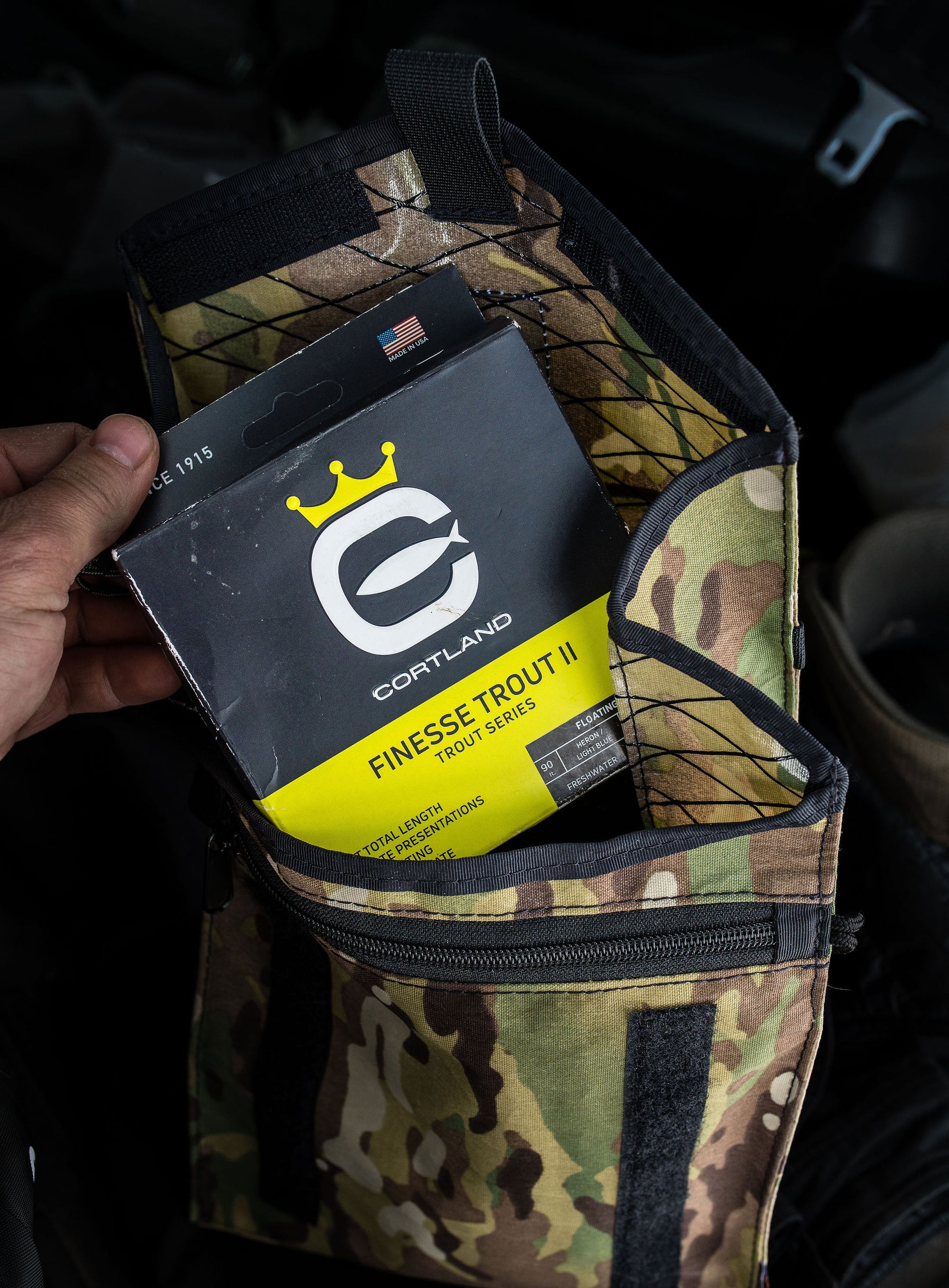 Someone pulling a Finesse Trout II box out of a camo bag