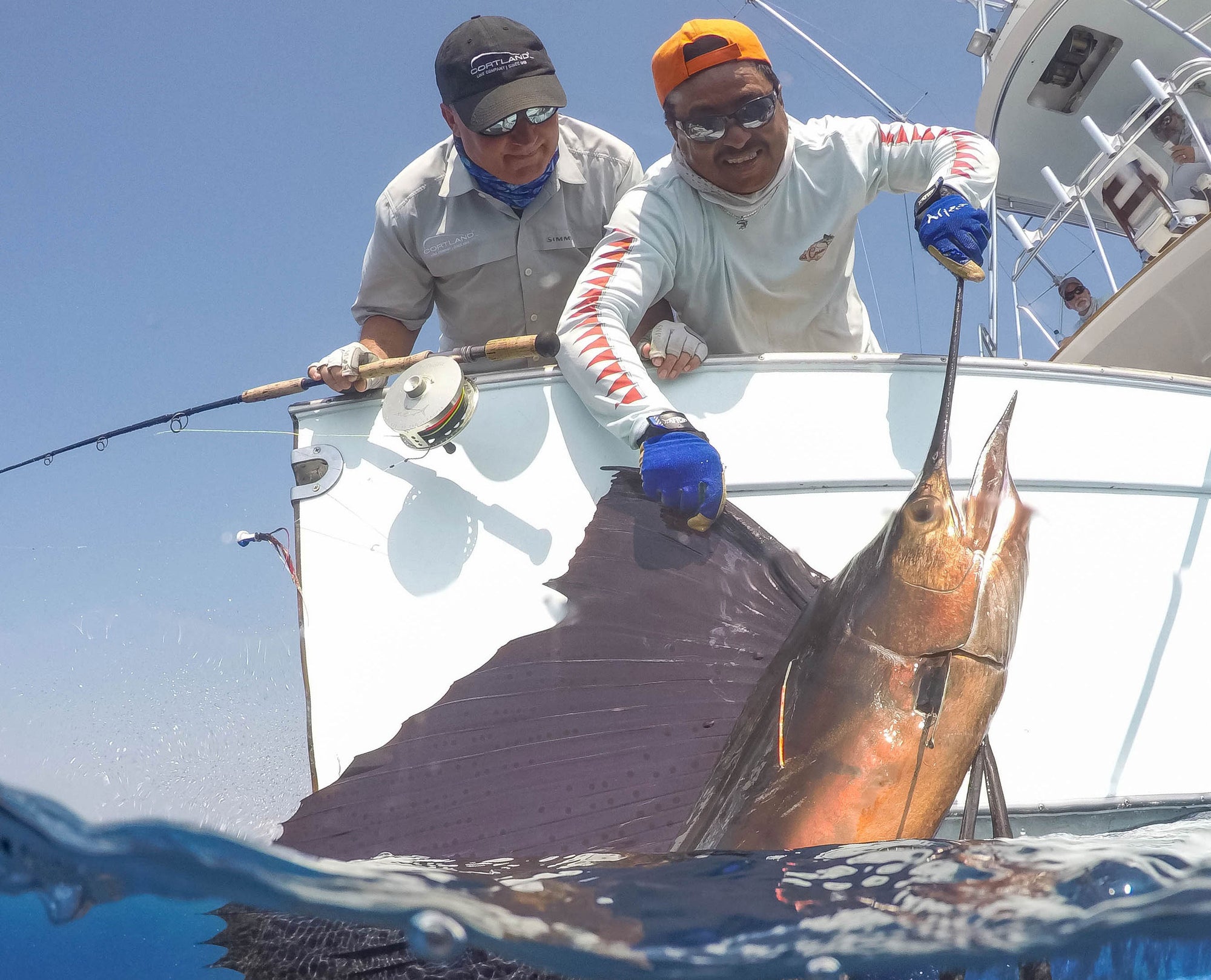 Two men pulling a swordfish onto their boat