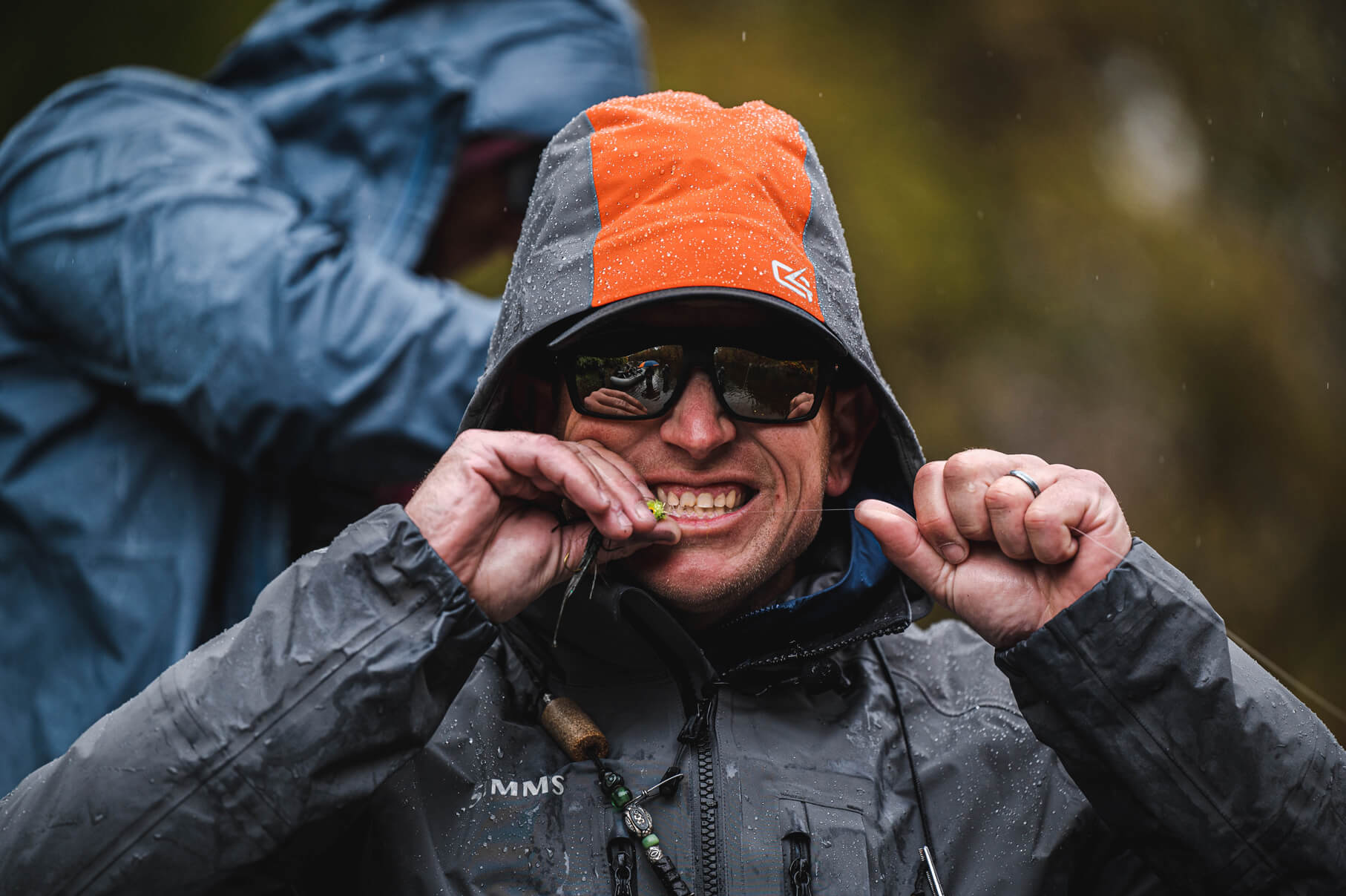 Fisherman biting his fly fishing tippet line to tighten it 