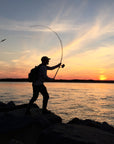 An individual is casting their fishing line with a sunset in the background. 