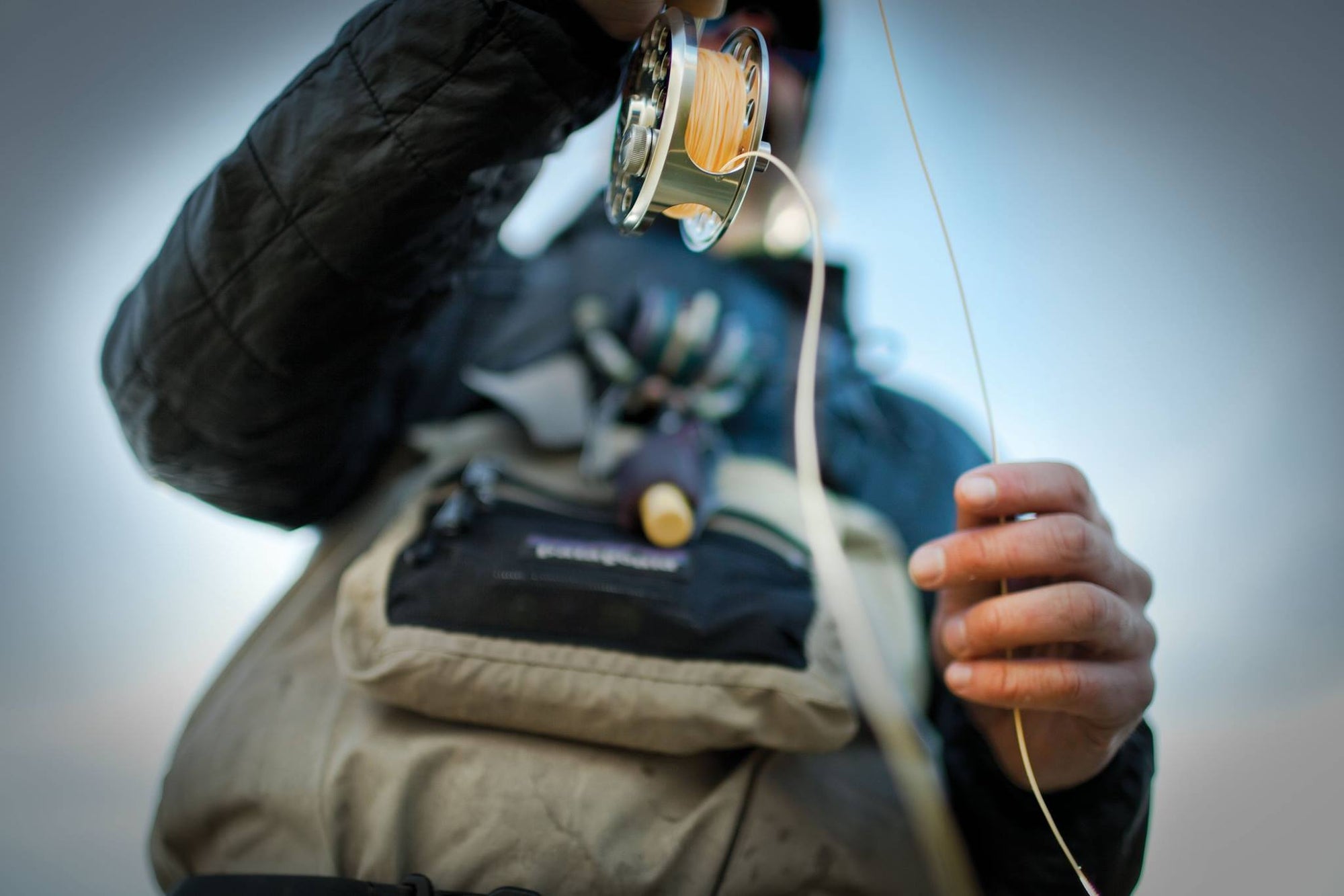 Bottom view of a fisherman holding onto his fly rod and reel